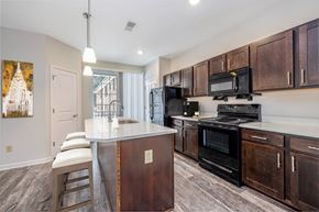Orchard Park townhouse for rent - A kitchen with dark wood cabinets and black appliances.