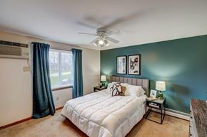 Tonawanda apartment for rent - A bedroom with a white bed and a ceiling fan.
