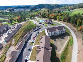Canonsburg apartment for rent - A large white building is surrounded by a parking lot and other buildings.