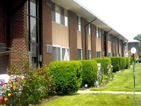 Webster apartment for rent - A building with a brick facade and windows with white curtains.