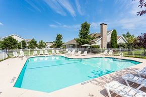 Webster apartment for rent - A large swimming pool surrounded by lawn chairs and trees.