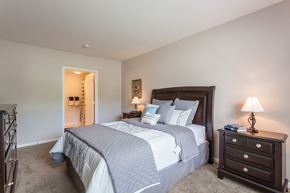 Webster apartment for rent - A bedroom with a large bed and a nightstand with a lamp.