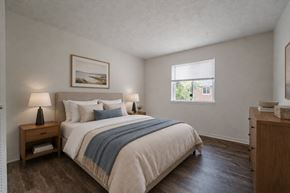 Webster townhouse for rent - A bedroom with a bed, nightstand, and a painting on the wall.