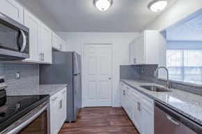Rochester apartment for rent - a kitchen with white cabinets and a stainless steel refrigerator