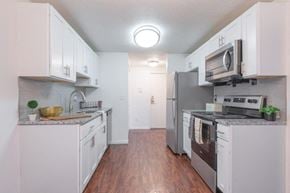 Rochester apartment for rent - a kitchen with white cabinets and stainless steel appliances