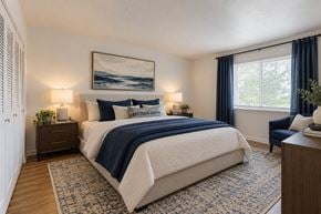 Rochester apartment for rent - A bedroom with a large bed and a painting on the wall.