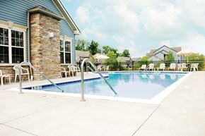 Webster apartment for rent - A pool with a stone pillar and a house in the background.