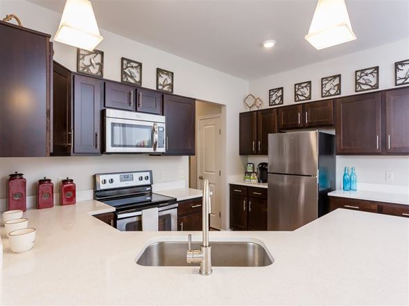 Webster apartment for rent - A kitchen with dark brown cabinets and a stainless steel refrigerator.