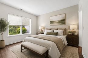 Canandaigua townhouse for rent - A bedroom with a large bed, a potted plant, and a painting on the wall.