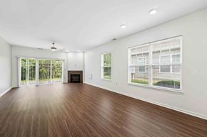 Canandaigua townhouse for rent - A spacious room with wooden flooring and a fireplace.