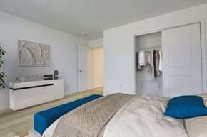 Canandaigua townhouse for rent - A bedroom with a bed, a bench, and a cabinet with a mirror above it.