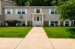 Penfield apartment for rent - A building with a white door and windows with trees in the background.
