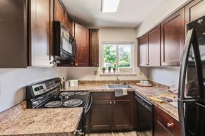 Penfield apartment for rent - a kitchen with black appliances and brown cabinets