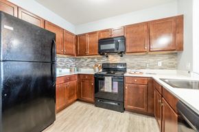 Rochester apartment for rent - a kitchen with wooden cabinets and black appliances