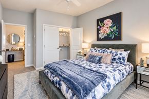 Rochester apartment for rent - A bedroom with a large bed and a painting on the wall.