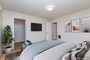 Oakland apartment for rent - A bedroom with a bed, a plant, and pictures on the wall.