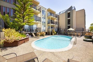 Oakland apartment for rent - A pool surrounded by chairs and plants in front of a building.