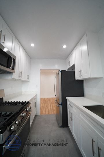 Los Angeles apartment for rent - A modern kitchen with white cabinets and a black stove top oven.