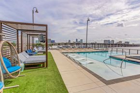 Jacksonville apartment for rent - a pool with lounge chairs and a city skyline in the background