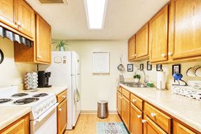 Jacksonville apartment for rent - galley kitchen with ample cabinetry, white appliances, and wood-style floors