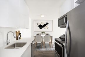 Burnaby apartment for rent - a kitchen with white cabinets and a sink and a table with chairs