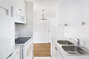 Calgary apartment for rent - kitchen with a double sink, a stove and a view to the dining room.