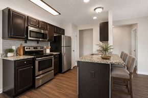 Victor apartment for rent - A kitchen with dark brown cabinets and a granite countertop.