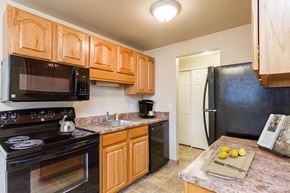 Rochester townhouse for rent - a kitchen with black appliances and wooden cabinets