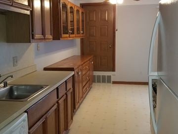Shelby Twp apartment for rent - a kitchen with wooden cabinets and a sink and a refrigerator
