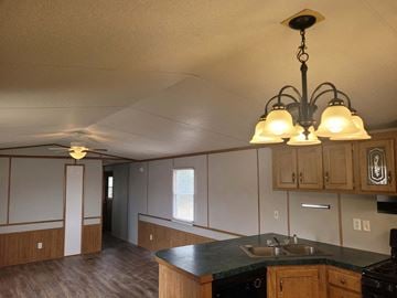 Shawnee house for rent - A kitchen with a black counter top and wooden cabinets.