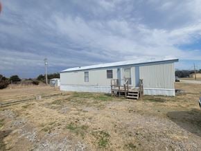 Shawnee house for rent - A metal building with a blue roof and a wooden staircase leading to the entrance.