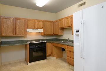 Vandalia apartment for rent - a kitchen with wooden cabinets and black counter tops and a refrigerator