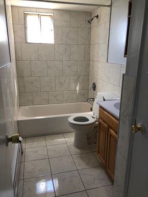 Paterson apartment for rent - A white tiled bathroom with a toilet, sink, and tub.