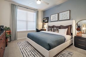 San Antonio apartment for rent - A bedroom with a large bed, a nightstand, and a plant.