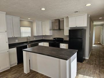 Shawnee house for rent - A kitchen with white cabinets and black appliances.