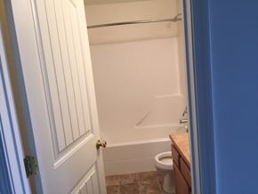 Sidney apartment for rent - the bathroom has a white tub and a toilet and a blue door