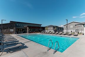Herriman townhouse for rent - A swimming pool with lounge chairs and a building in the background.