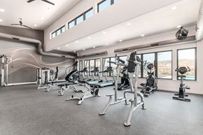 Herriman townhouse for rent - A spacious gym with various exercise equipment and a ceiling fan.