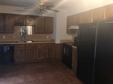 Guthrie house for rent - A kitchen with wooden cabinets and black appliances.