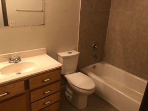 Guthrie house for rent - A white toilet sits next to a bathtub in a bathroom.