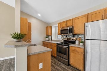 Farmington apartment for rent - A kitchen with wooden cabinets and a stainless steel refrigerator.