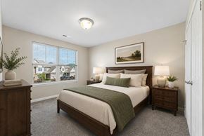 Farmington apartment for rent - A bedroom with a large bed, a nightstand, and a window overlooking a residential area.