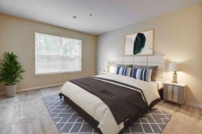 Farmington apartment for rent - A bedroom with a large bed and a potted plant.