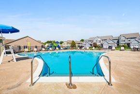 Farmington apartment for rent - A large blue swimming pool with a ladder and a blue umbrella.