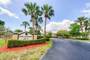 Jensen Beach apartment for rent - Drive into Villa Assumpta with monument signage with shrubs and palm trees