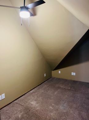Jonesboro apartment for rent - A ceiling fan with a light is mounted on a wall in a room with a carpeted floor.