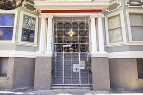 San Francisco apartment for rent - A white door with a metal grill is in front of a building.