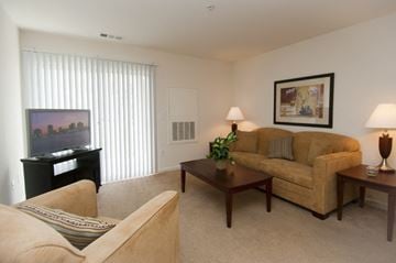 Salisbury apartment for rent - A living room with a tan couch, a brown coffee table, and a painting on the wall.