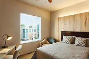 Cleveland apartment for rent - A bedroom with a large bed and a window overlooking a cityscape.