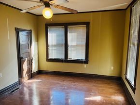 Jonesboro house for rent - an empty living room with a ceiling fan and two windows